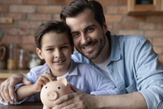 padre e figlio davanti a salvadanaio a forma di maialino